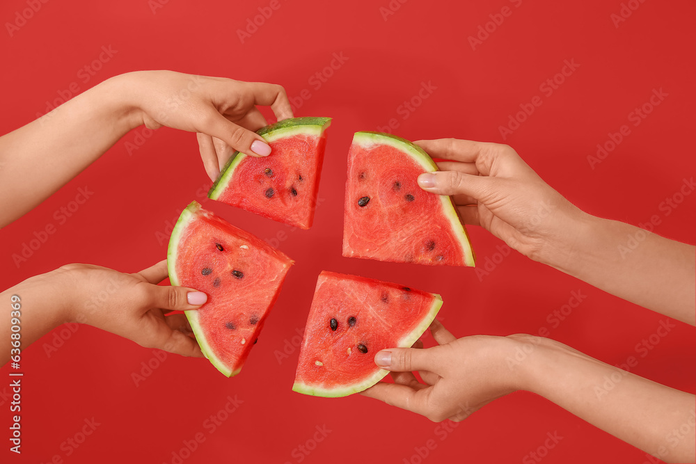 Female hands with pieces of ripe watermelon on red background