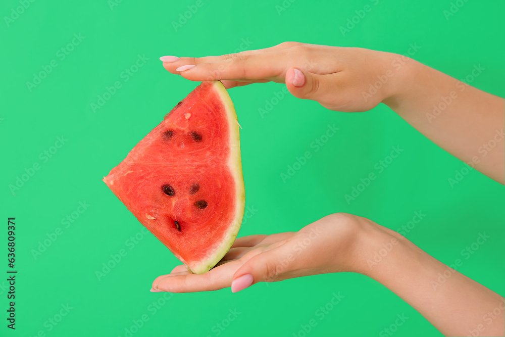 Female hands with piece of ripe watermelon on green background, closeup