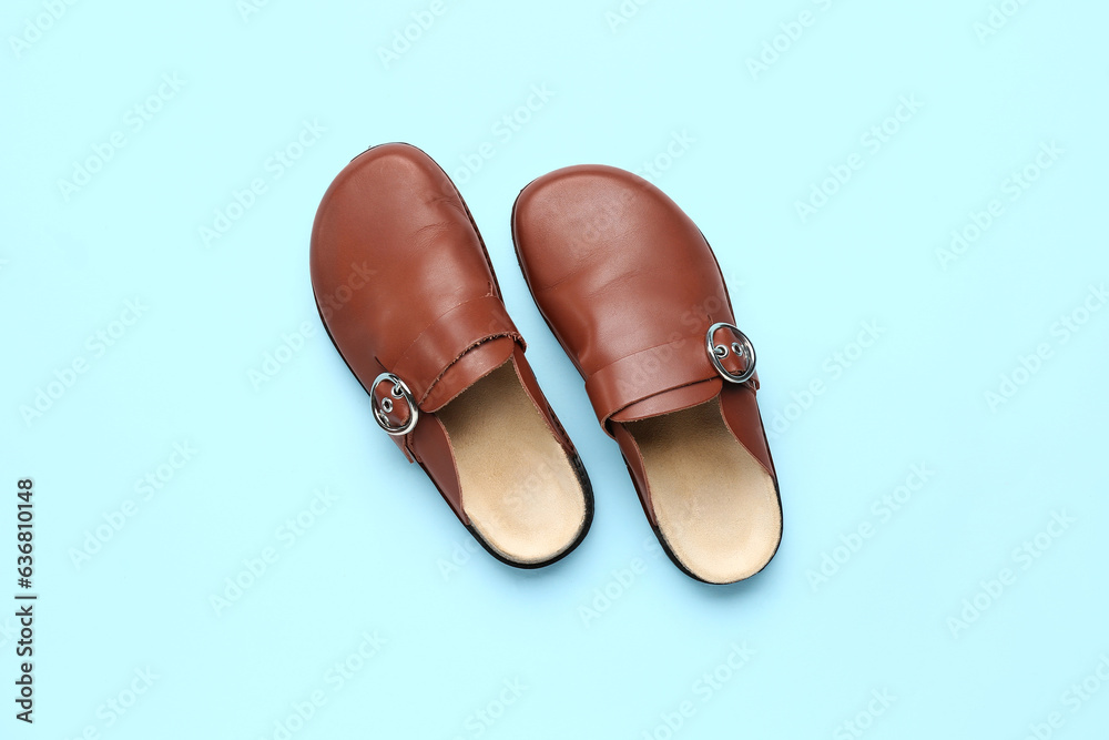 Pair of leather orthopedic slippers on color background