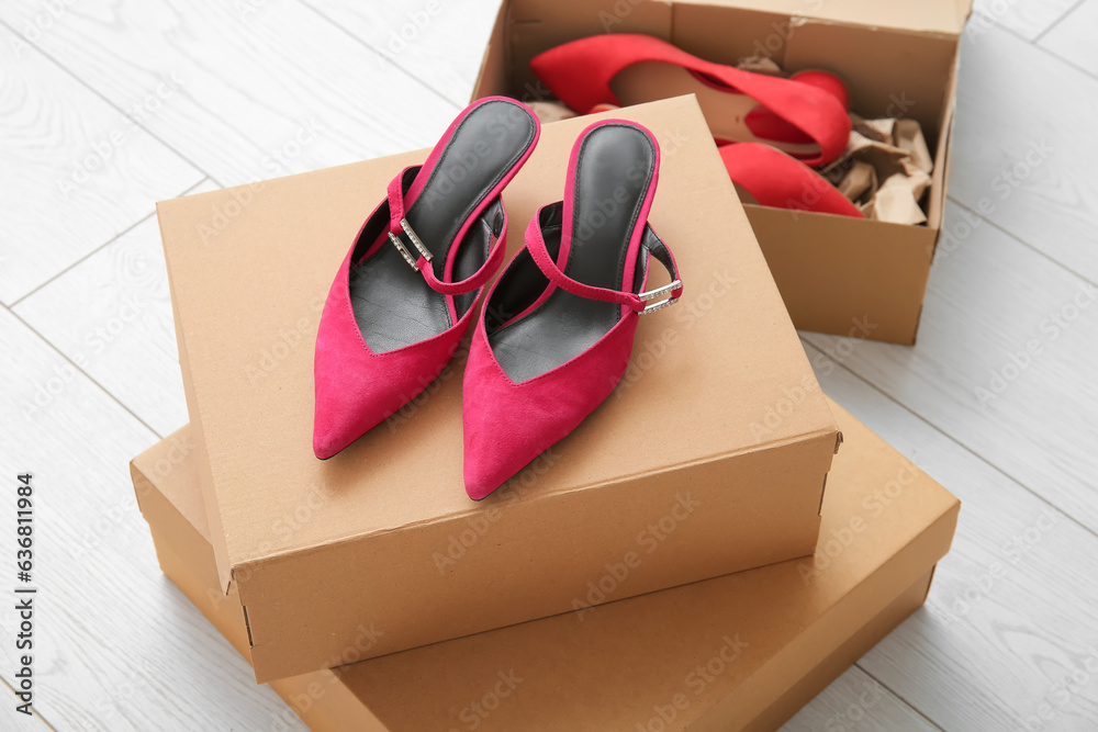 Boxes with stylish high heeled shoes on floor, closeup