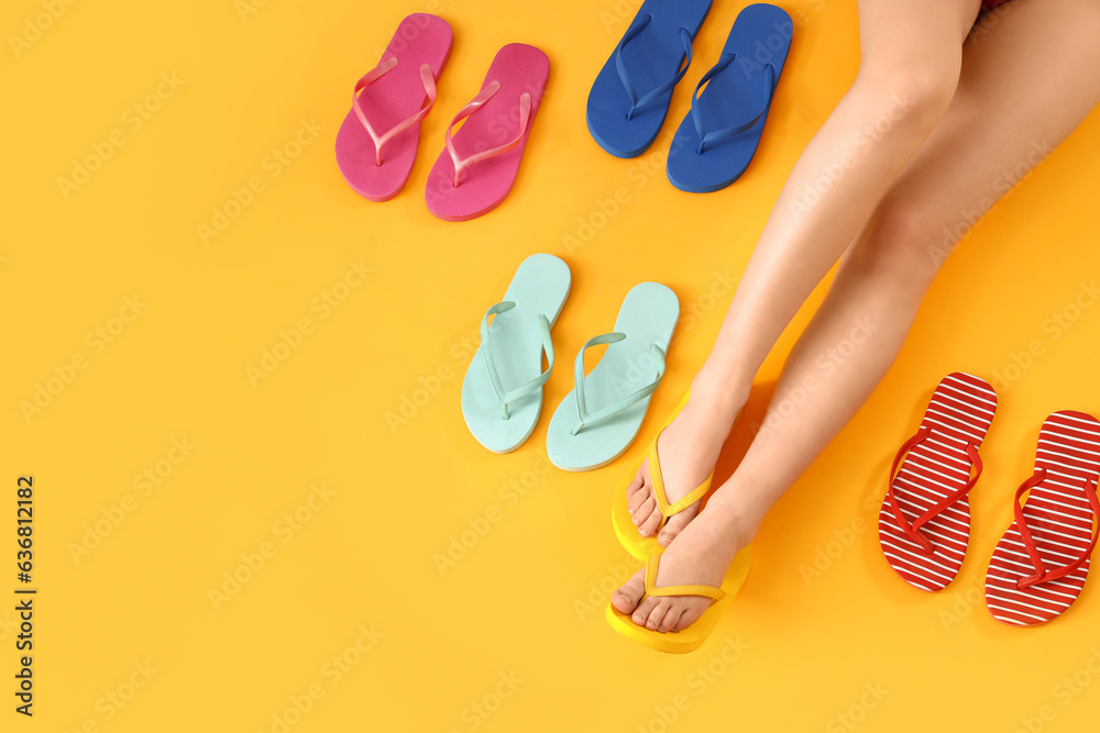 Female legs with different colorful flip flops on yellow background