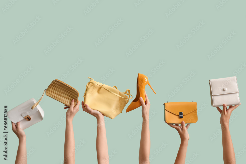 Many female hands holding different stylish bags and high heels on pale green background