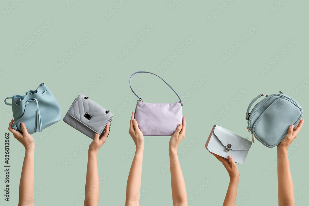 Many female hands holding different stylish bags on pale green background