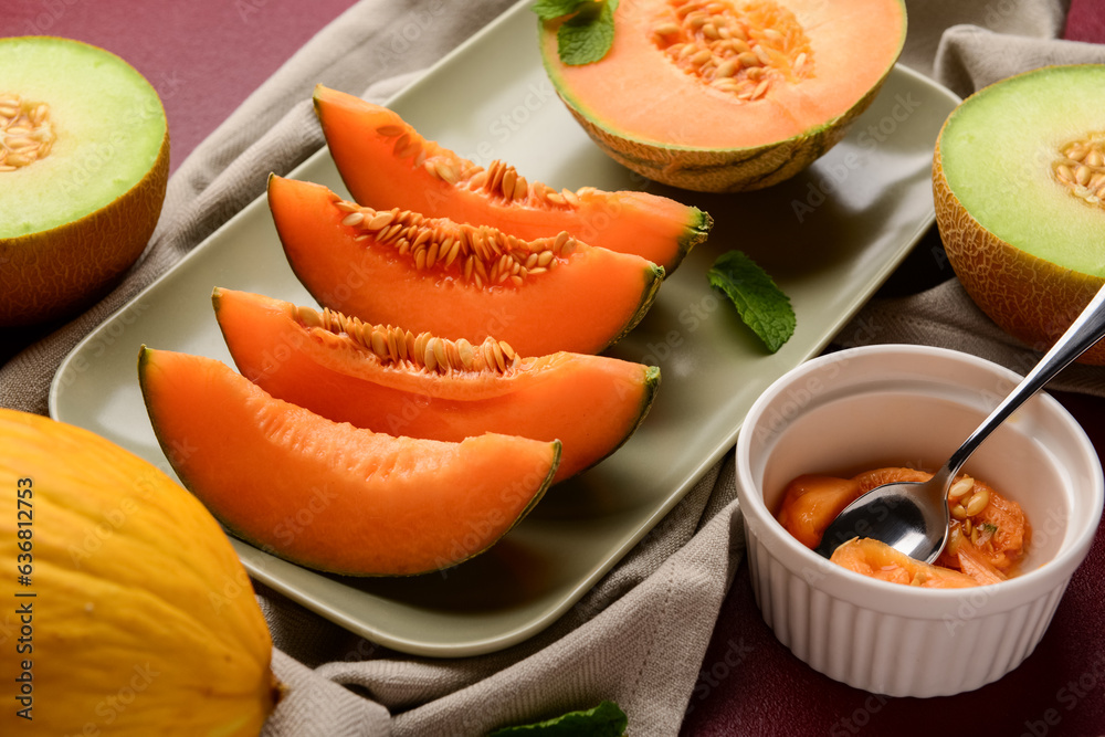 Plate with tasty ripe melons on red background