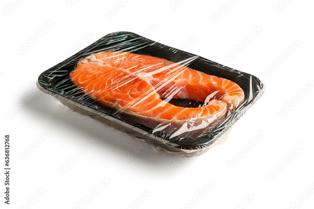 Fresh salmon steak in plastic food wrap on white background