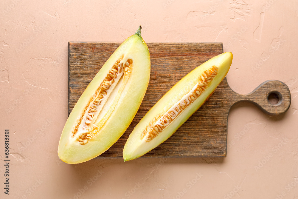 Wooden board with pieces of sweet melon on pink background