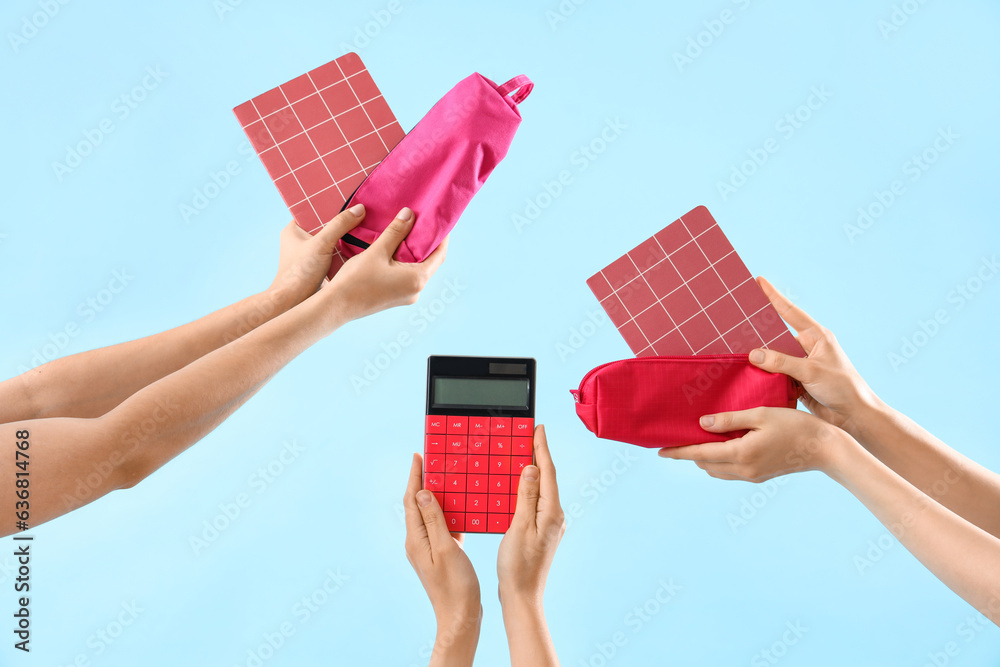 Many female hands with notebooks, pencil cases and calculator on blue background