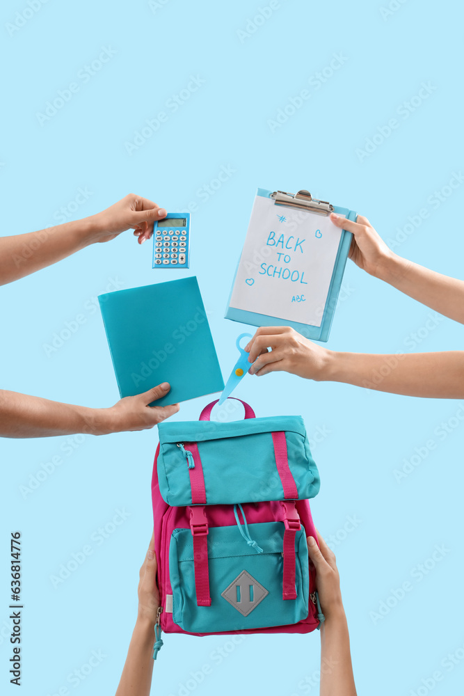 Female hands holding stationery, backpack and notebooks with text BACK TO SCHOOL on blue background