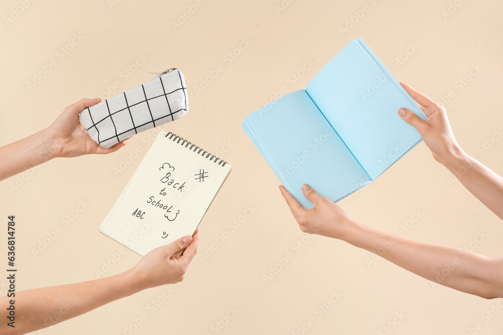 Female hands holding pencil case and notebooks with text BACK TO SCHOOL on beige background