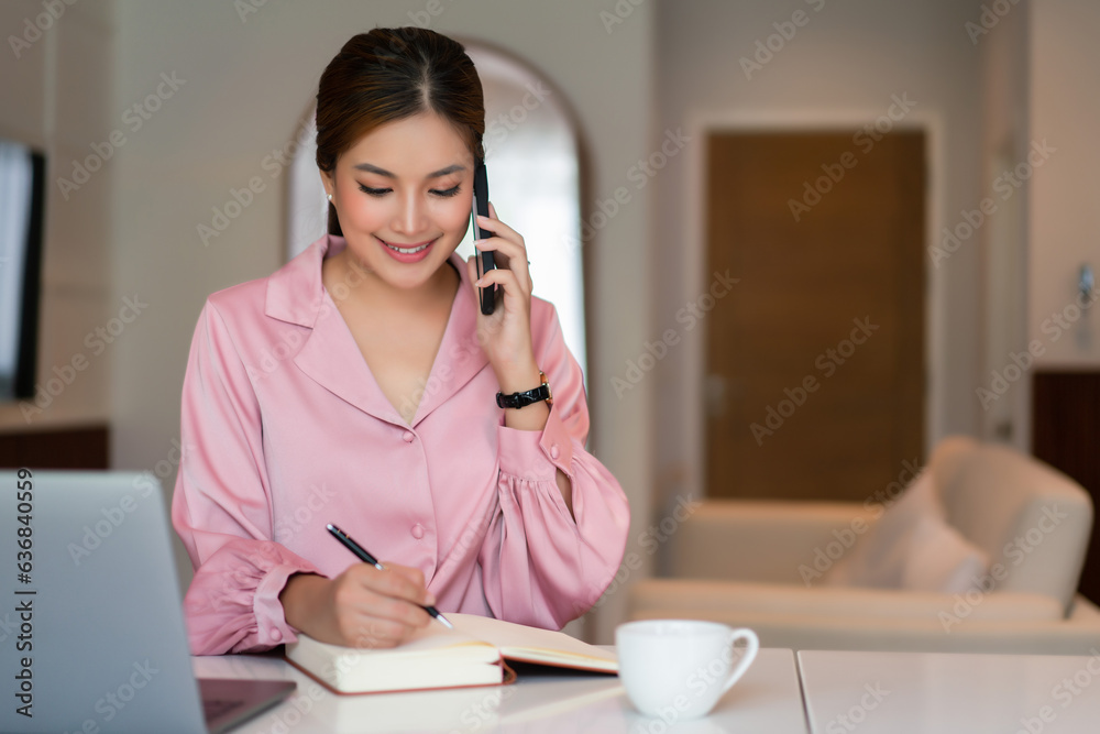 Businesswoman use smartphone to talking with client and taking notes while working in home office