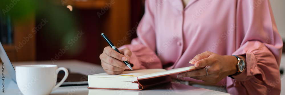 Female entrepreneur write data in notebook while working about strategy new startup in home office