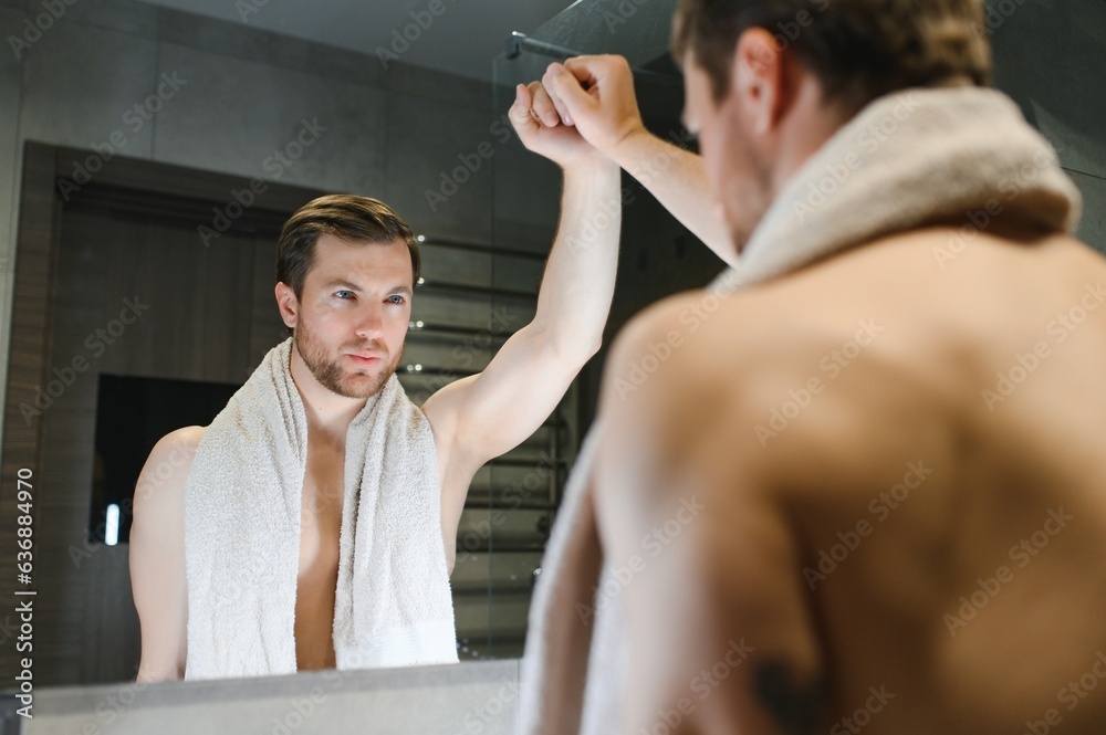 Young man looking in mirror after shaving at home