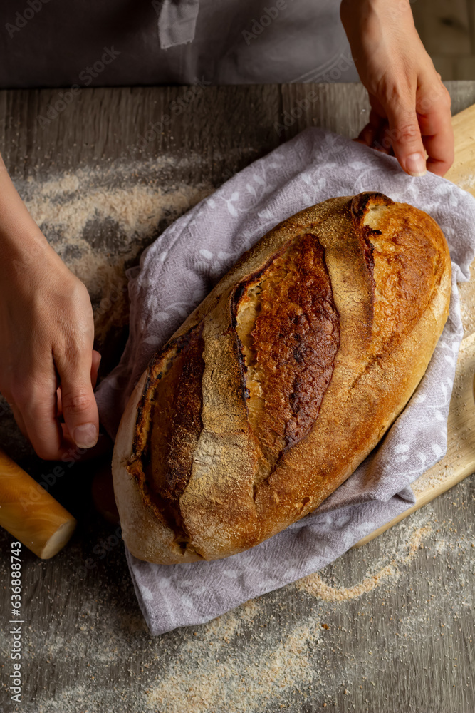 Close-up of freshly baked bread in hands on a wooden board background.