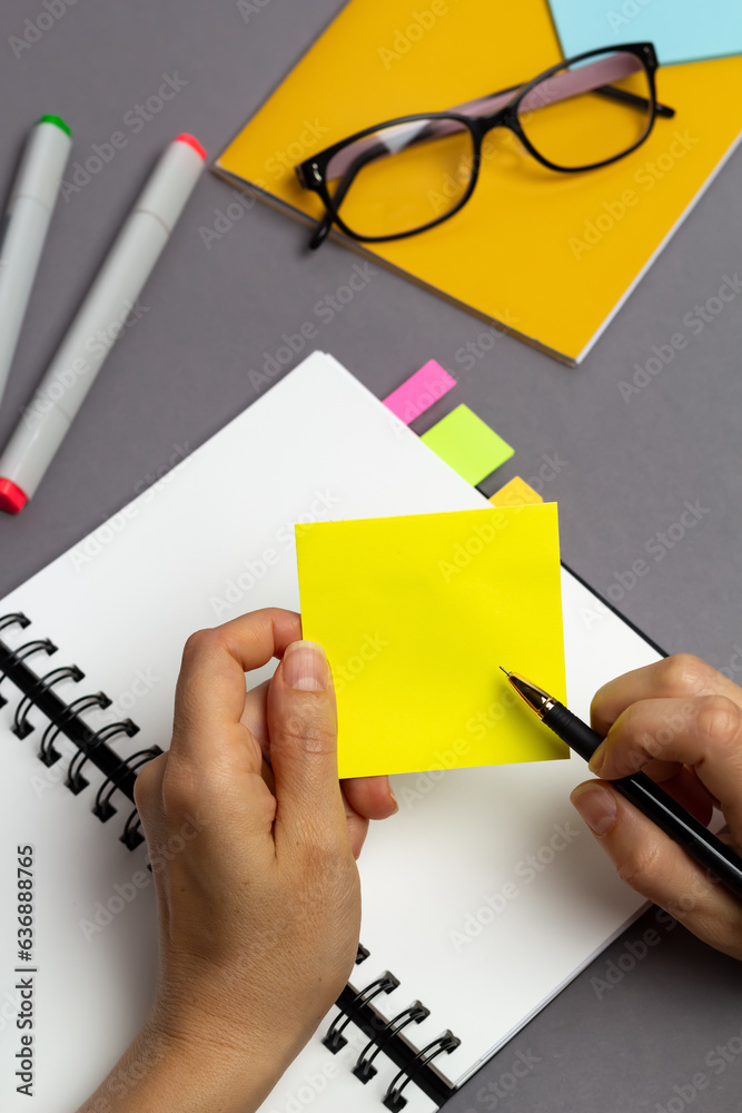 Business planning concept. Hand with a pen and a blank sticker to write a note on the desktop.