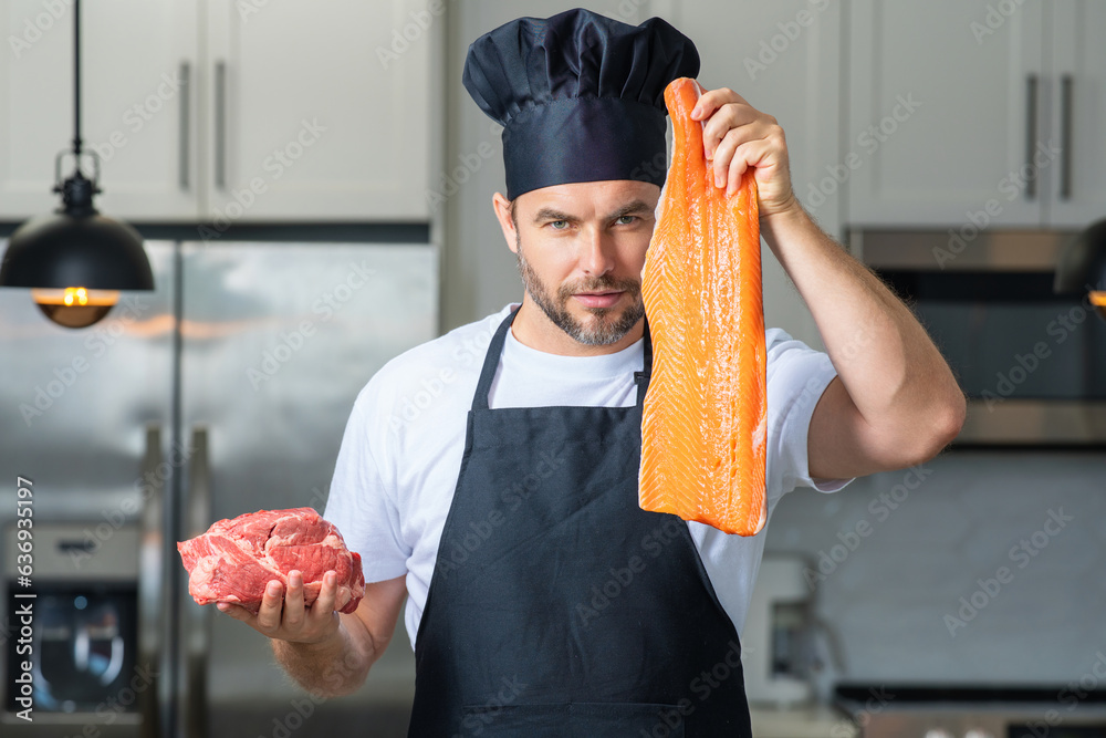 Portrait of chef man hold fish and meat, salmon and beef in a chef cap in the kitchen. Man wearing a