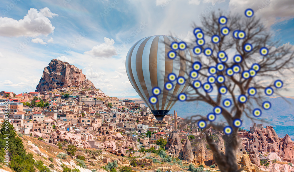 Hot air balloon flying over spectacular Cappadocia - Carved houses in rock and an Nazar (evil eye) t