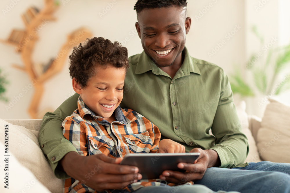 Happy Black Man And His Son Using Digital Tablet Indoors