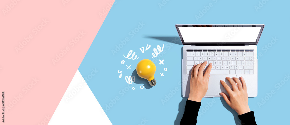 Person using a laptop computer and a light bulb - Flat lay