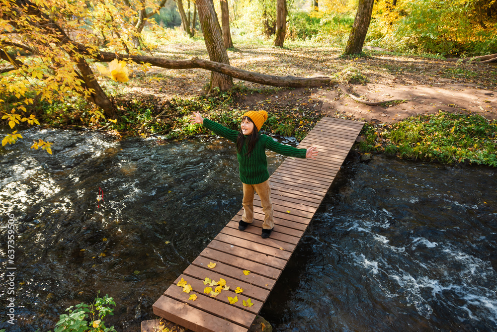 Child play with dry yellow leaves in an autumn park. Kid throw and scatter autumn leaves.