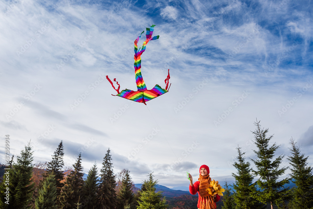 Small happy child runs and plays with kite in the autumn season. Blue sky with clouds background. Wi