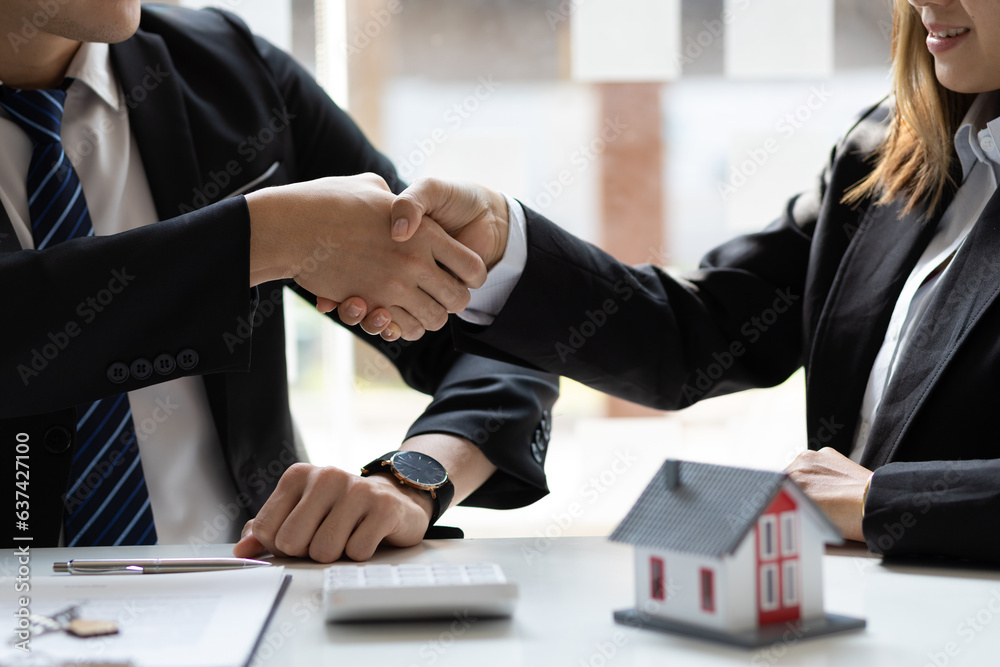 Business people shake hands with colleagues at a meeting.