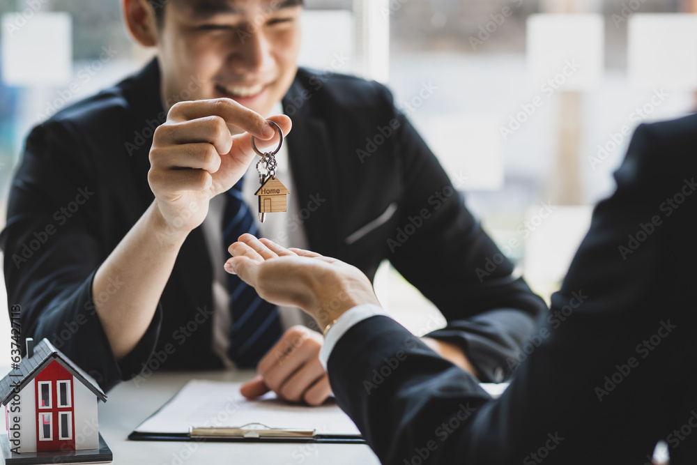 Real estate agent hands over the house keys to a homebuyer after the purchase agreement has been sig