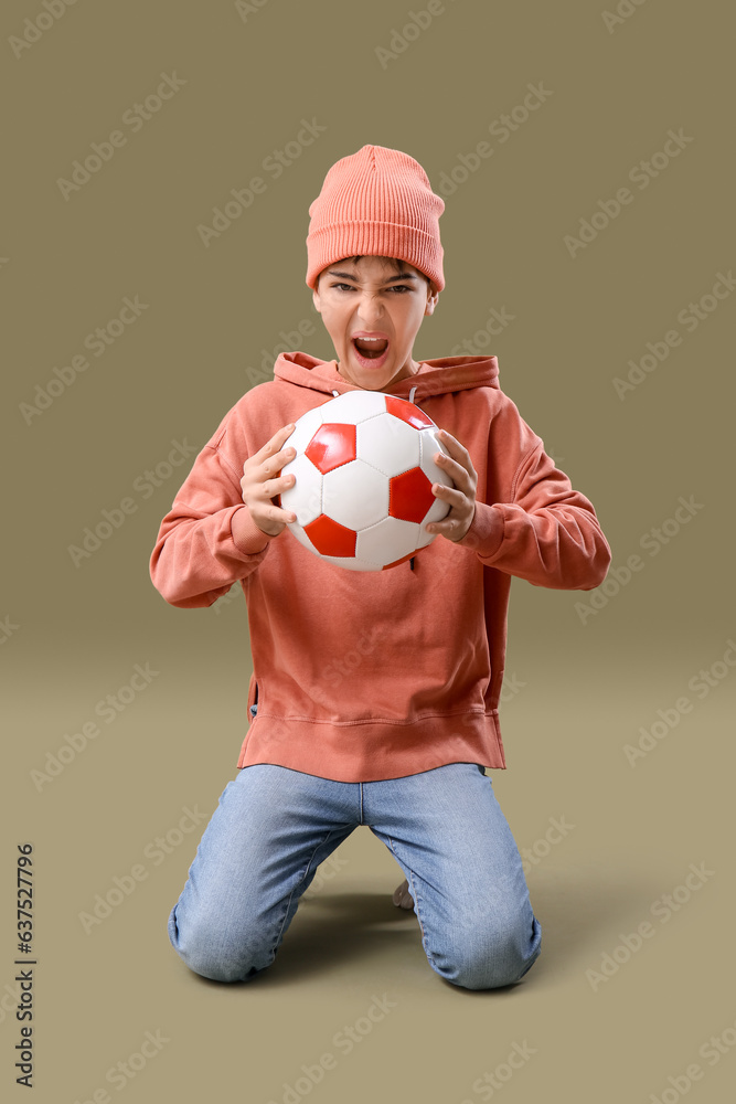 Aggressive little boy with soccer ball on color background