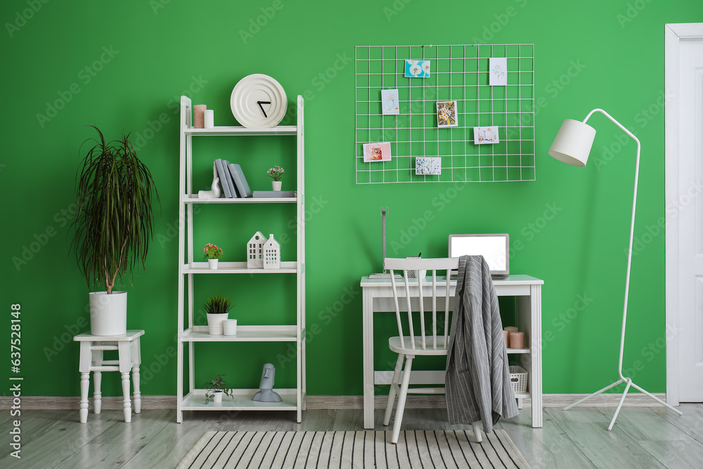 Interior of room with shelving unit and stylish holder for books near green wall