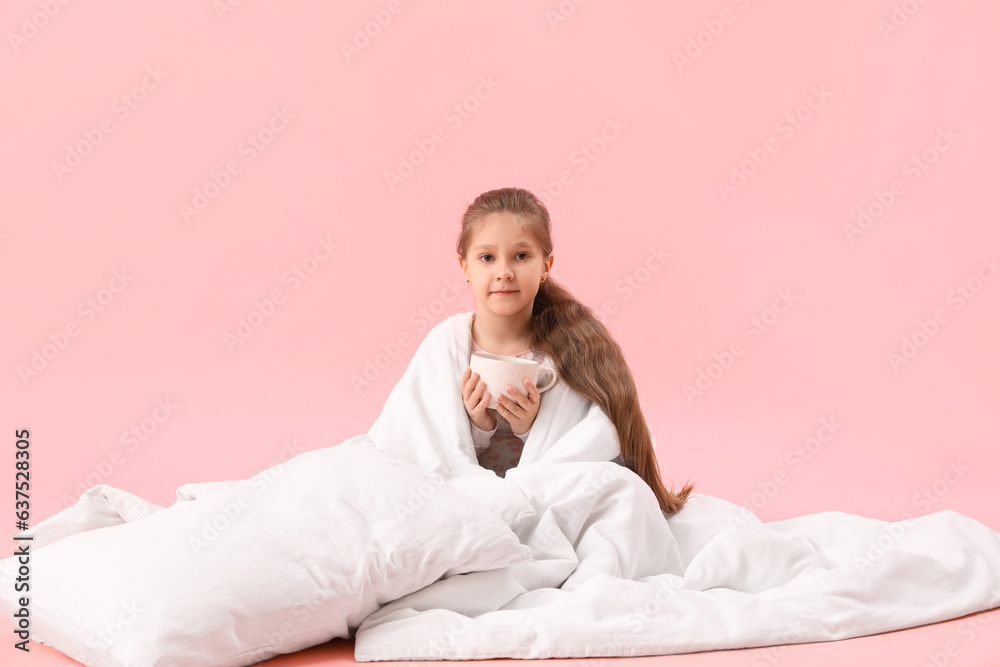 Little girl with cup of cocoa and soft blanket on pink background