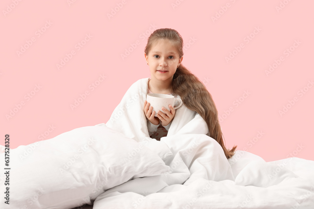 Little girl with cup of cocoa and soft blanket on pink background