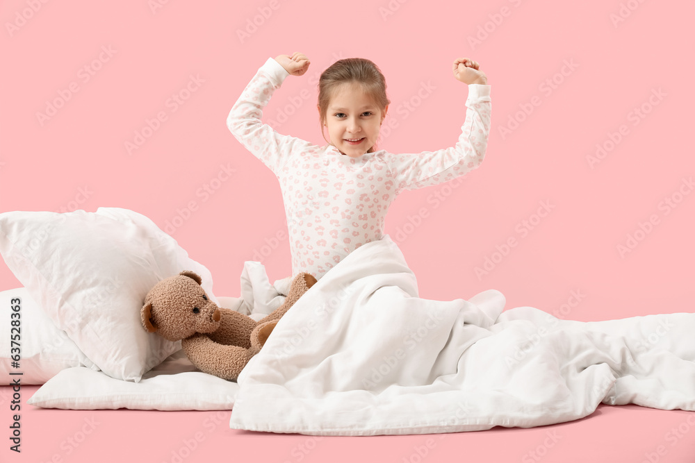 Little girl with soft blanket waking up on pink background