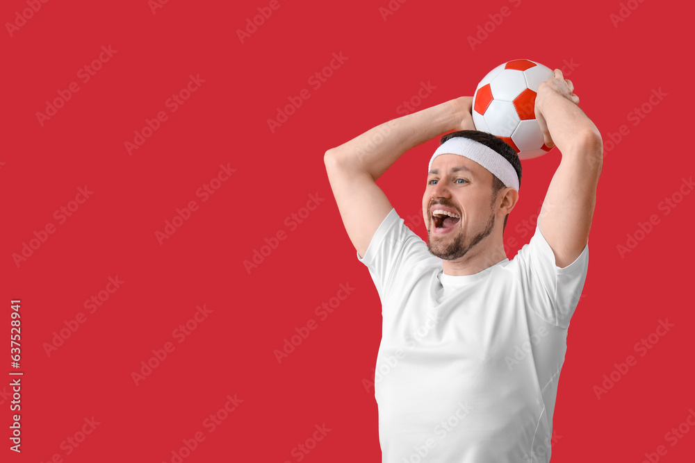 Happy soccer player with ball on red background