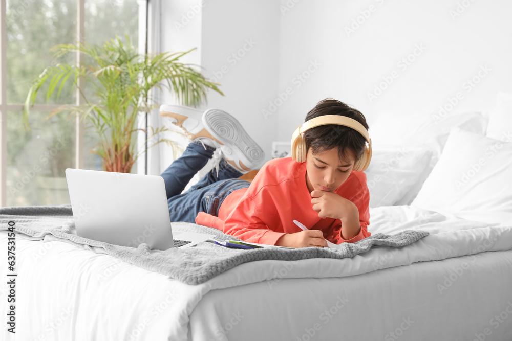 Little boy with headphones studying in bedroom