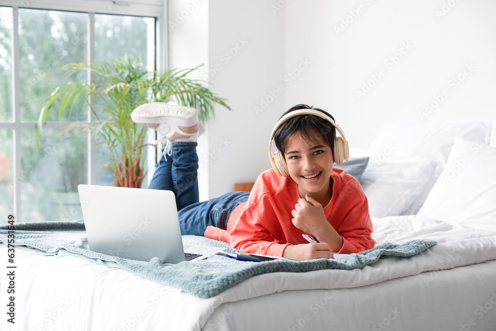 Little boy with headphones studying in bedroom