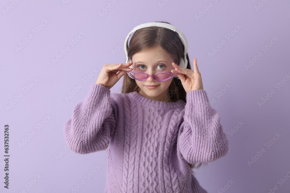 Little girl in headphones on lilac background