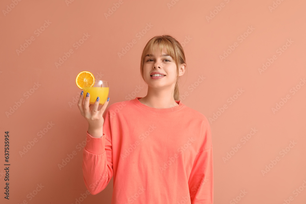 Teenage girl with glass of orange juice on pink background