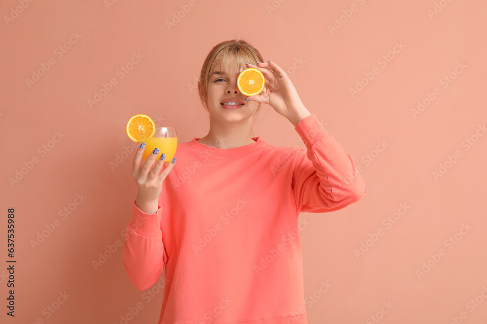 Teenage girl with glass of juice and orange on pink background