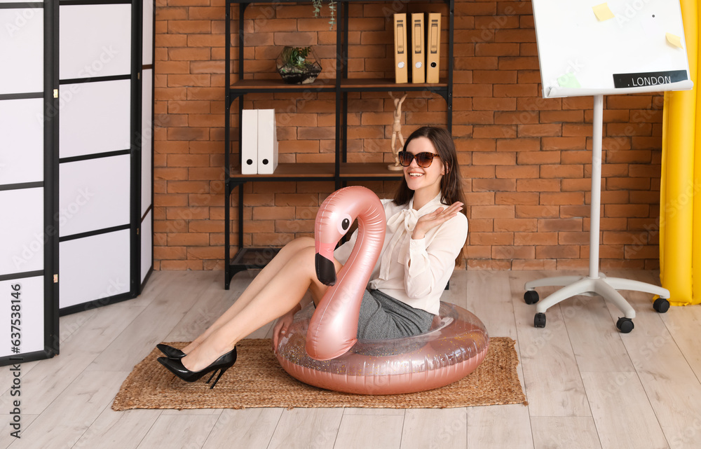 Young businesswoman with swim ring ready for summer vacation in office