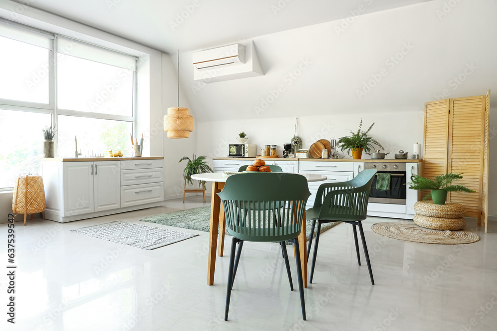 Interior of modern kitchen with white counters and dining table