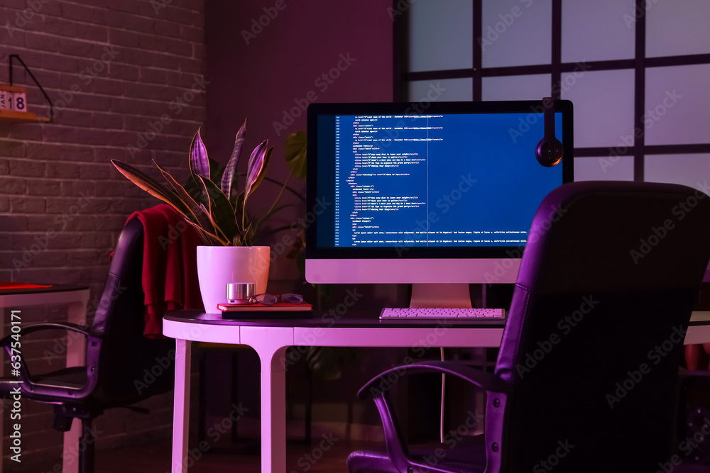 Programmers workplace with computer in dark office