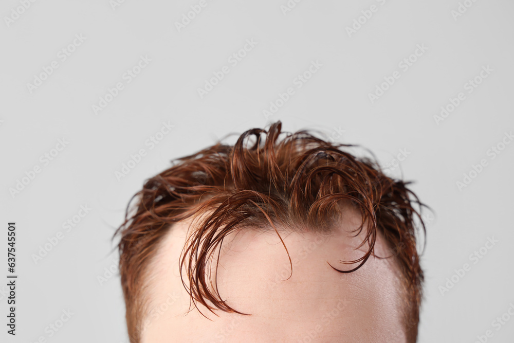 Young man with wet hair on light background