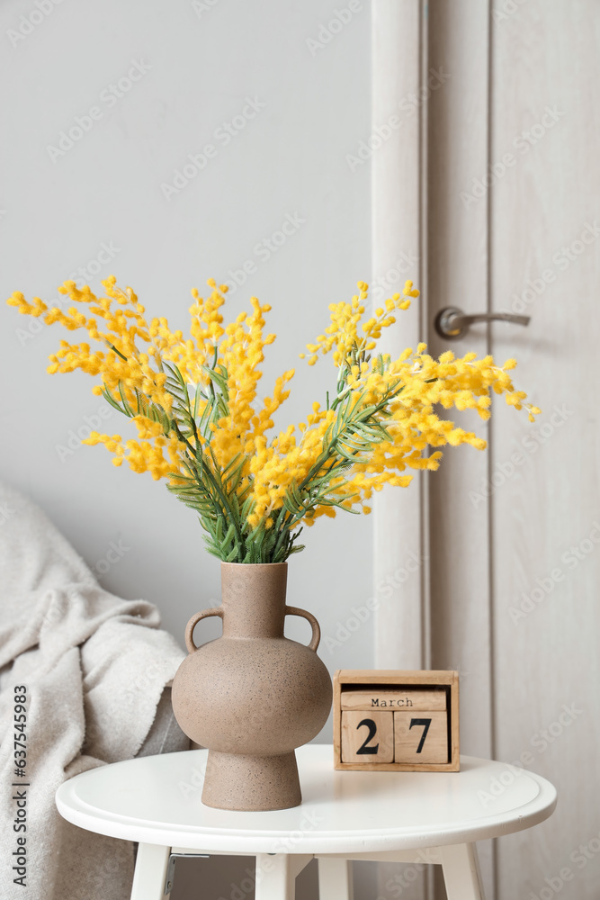 Vase with beautiful mimosa flowers on end table in living room, closeup