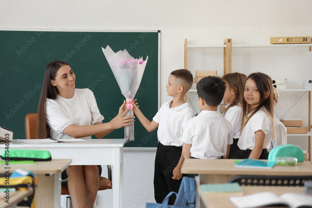 Little school children greeting teacher in classroom