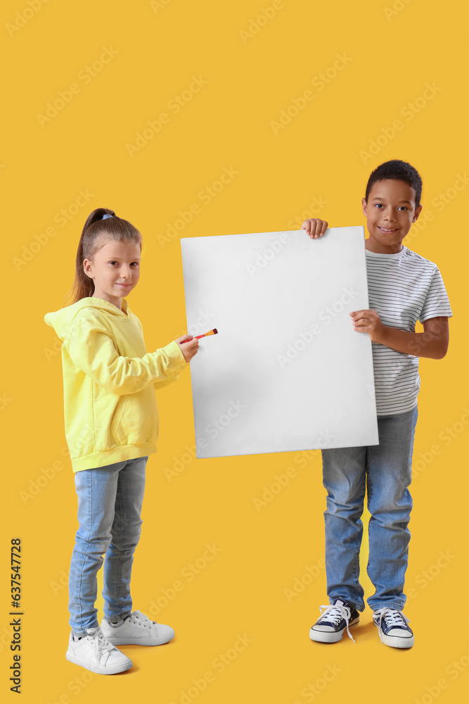 Cute little children with blank poster and brush on yellow background