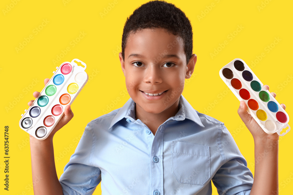 Little African-American boy with paints on yellow background, closeup