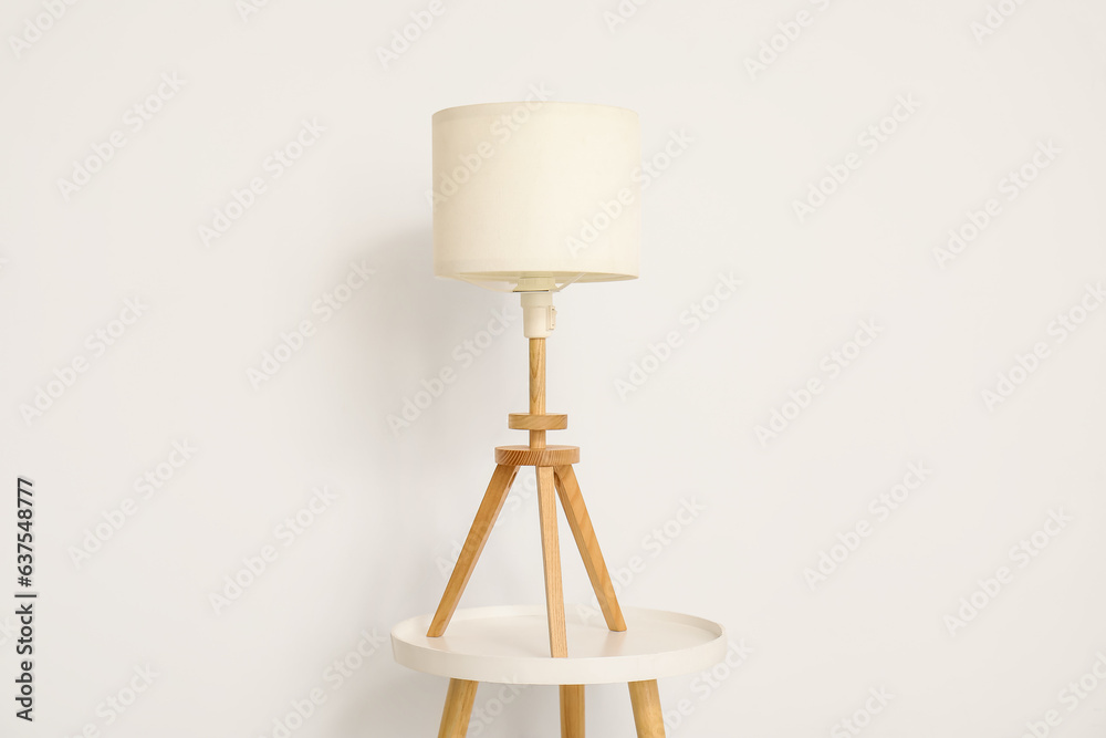 Lamp on small table near white wall