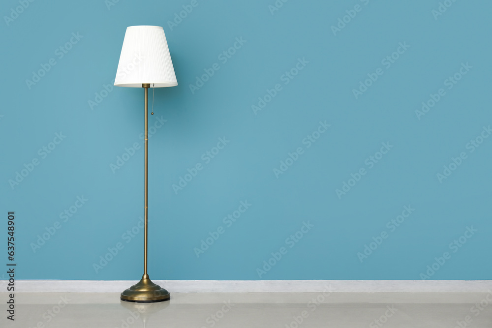 White standard lamp near blue wall