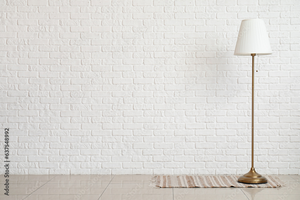 Standard lamp near white brick wall