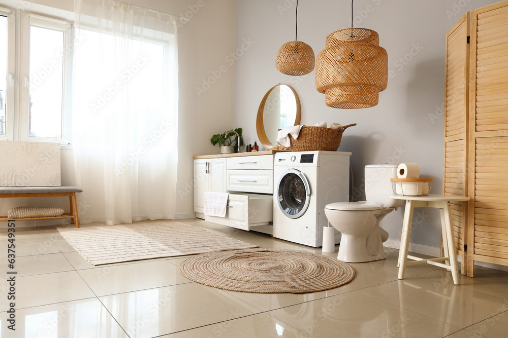 Interior of light restroom with ceramic toilet bowl and washing machine