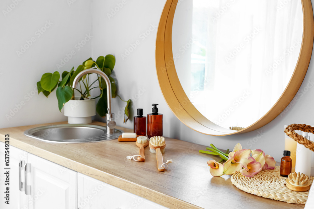 Mirror, bath accessories and sink on wooden countertop in bathroom, closeup